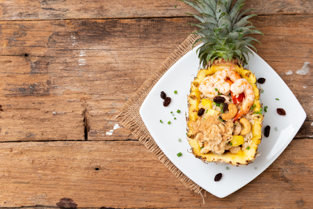 Pineapple fried rice with seafood served in a pineapple on the wooden tableの写真素材