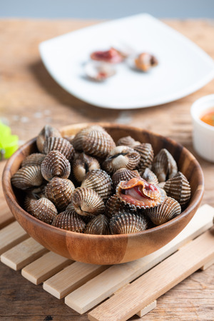 Steamed cockle ( Boiled cockles ) with spicy seafood sauce on wooden backgroundの写真素材