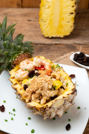 Pineapple fried rice with seafood served in a pineapple on the wooden tableの写真素材