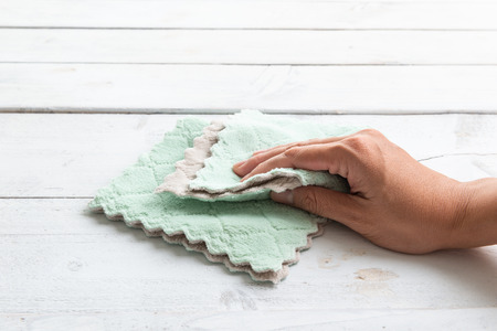 Hand cleaning spot from wooden  table surface with table wipes