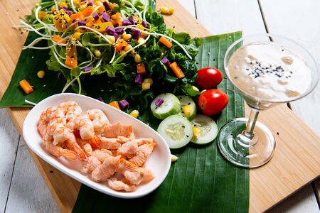 Fresh salad plate with shrimp, salmon, tomato and mixed greens  on wooden background close up. Healthy food. Clean eating.の写真素材