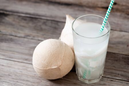 Fresh coconut juice in a glass with coconut white meat and peeled coconut on wood background.の写真素材