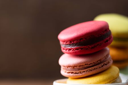 Pile of sweet and colorful french macaroons on wooden background.