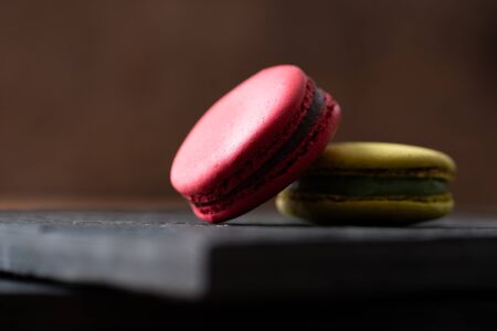 Pile of sweet and colourful french macaroons on wooden background.