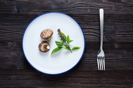 Shiitake mushrooms (Lentinus edodes) in white plate on the wooden background.の写真素材