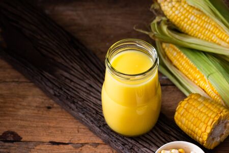Fresh sweet corn juice (corn milk) and corn on wooden background
