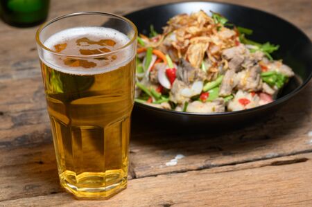 Glass of cold light beer with snacks on a wood backgroundの写真素材
