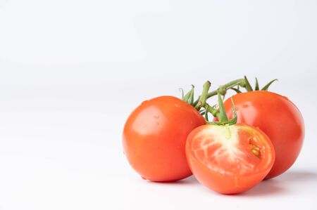 Fresh tomatoes on a green stem on white backgroundの写真素材