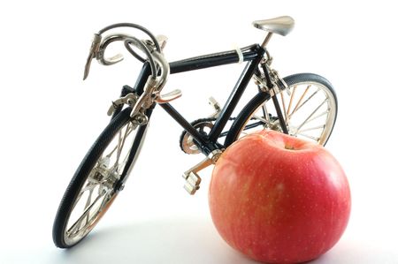 Toy bike standing next to red appleの写真素材