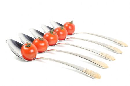 Metal steel spoons with cherry tomatos in it, on a white backgroundの写真素材