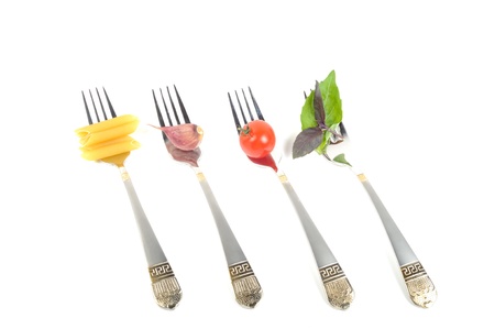 Cooking concept,four forks with tomato, garlic and pasta, closeup, on a white background