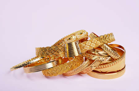 Womans precious golden bracelets, on a pink