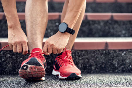 Close up, Athletics man tying shoelace on the stairs.Get ready to start exercising or running.healthy lifestyle concept.の写真素材