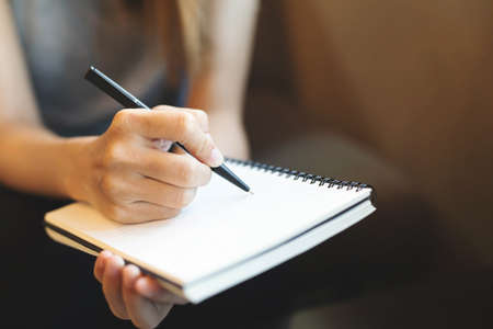 Close up image of young business woman writes with a pen in diary notepad, business and education concept.の写真素材