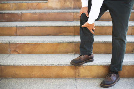 A man standing on the stairs have the sore pain and painful knee problem.walk up and down stairs accident. Health care concept.の写真素材