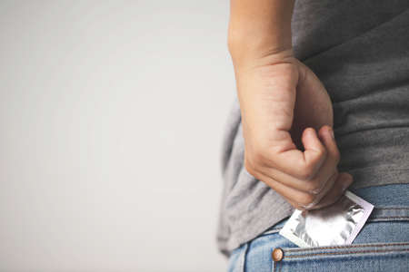 Image of the young man took a condom from his pocket jeans. Ready for safe sex and prevent infection.の写真素材