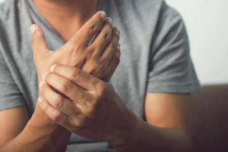 Image of a man in a gray shirt pain in hands,arthritis inflammation,wrist symptomatic.Office Syndrome.の写真素材