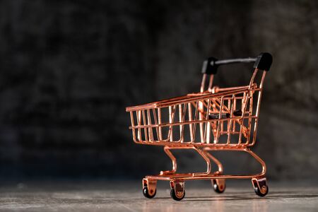 Mini shopping cart toy in copper color with dim light in the backgroundの写真素材
