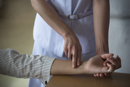 A nurse is checking the patient's radial artery pulse rate in the doctor's office.