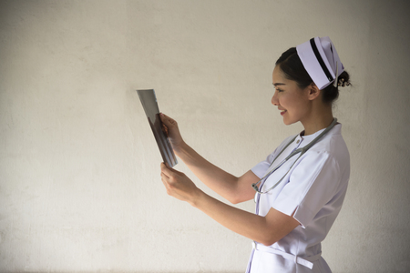 A beautiful nurse with stethoscope is looking at x-ray of foot in the hospital.の写真素材