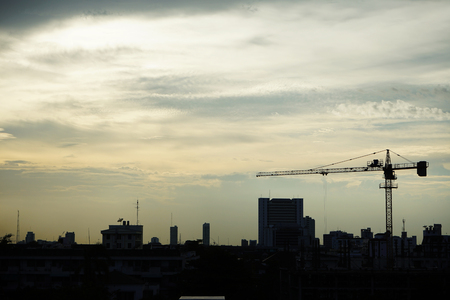 A crane, buildings telephone tower and satellite receiver in a cloudy dayの写真素材