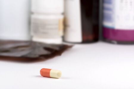 A capsule of medication in orange-yellow color and bottles of drugの写真素材