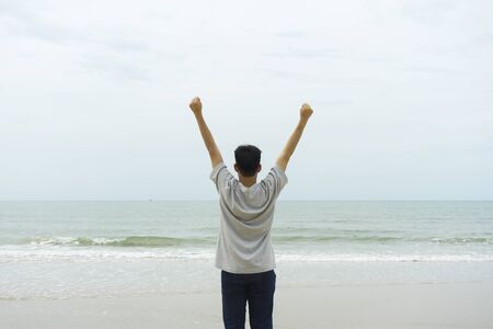 A man feeling success and raising the arms on the beachの写真素材