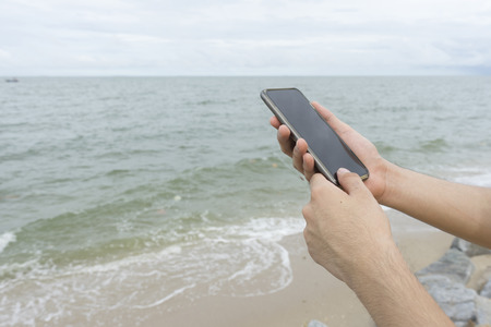 A man holding cellphone on the beachの写真素材