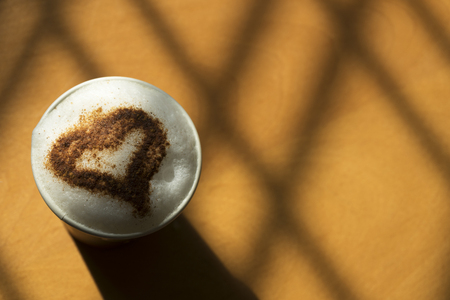 Top view of a paper cup of cappccino on the wooden table in the morningの写真素材