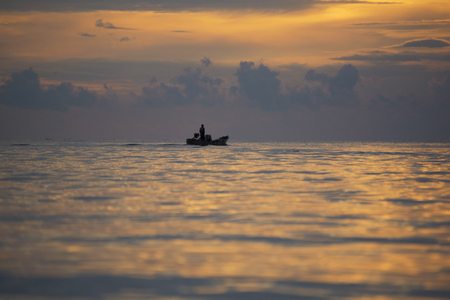 A fisherman on the boat in the morningの写真素材