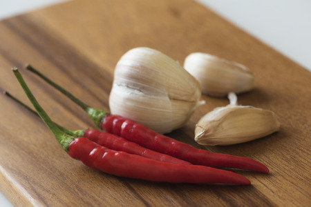Red chilies and garlics on wooden chopping boardの写真素材