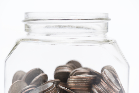 Close-up of coins in the clear bottle on white backgroundの写真素材