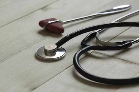 A black stethoscope and reflex hammer on wooden backgroundの写真素材