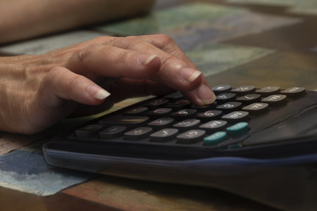 A female hand using a calculator on the table