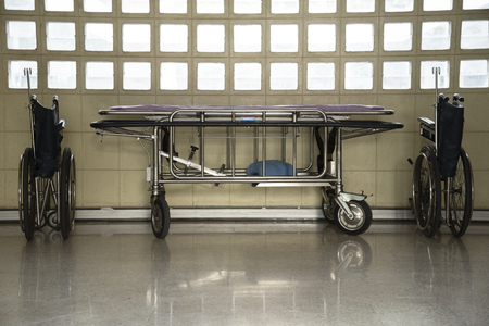 Two wheelchairs and a stretcher troller parking in the buildingの写真素材