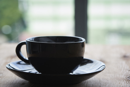 A black cup of hot coffee on the wooden tableの写真素材