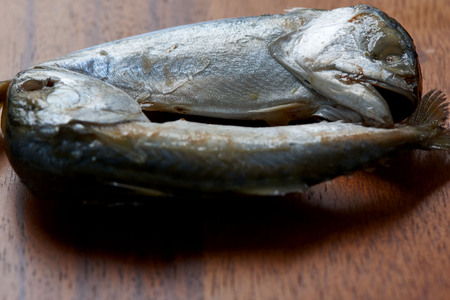 Two boiled mackerels from Maeklong river,identifying by their crooked heads and bent necks, on wooden boardの写真素材