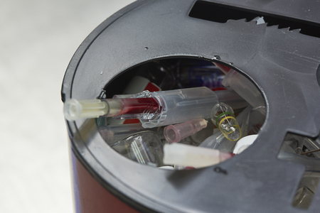 Sharp objects including used needle, used injected drug in red container for biohazard in operating roomの写真素材