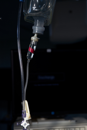 Intravenous saline fluid in a plastic bottle in operating room and monitoring display on backgroundの写真素材