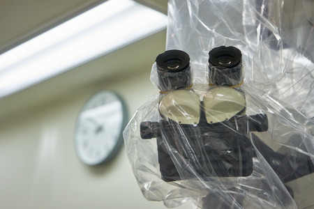 A draped surgical microscope in operating room. Background of a clock on the wallの写真素材