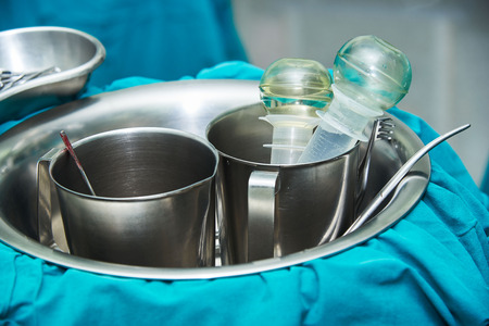 Irrigation, suction tube stained with blood, scissor, retractor in the stainless bowl in operating...