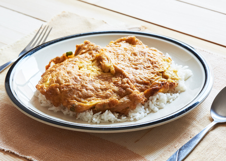 A plate of delicious Thai style pork omelette on top of rice on the tableの写真素材