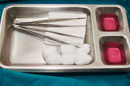 A silver tray of wound dressing set including two forceps, gauzes, cottons, pink antisepticの写真素材