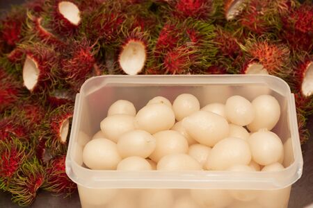 Rambutans in plastic container and shells after peeledの写真素材