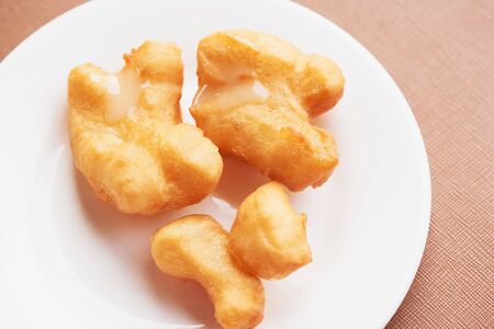 A plate of delicious deep fried dough stick with sweetened condensed milk on top.