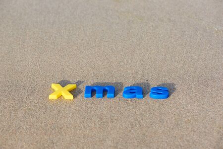 Merry Christmas. Letter in different colors on the sand and morning sunlight and shadow.の写真素材