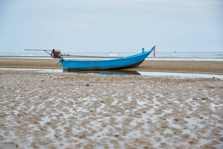 An old blue fisherman boat on the beach in cloudy day