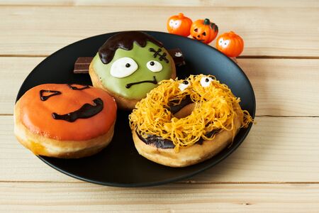 A plate of delicious halloween doughnut on wooden backgroundの写真素材