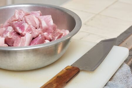 Raw pork meats in the stainless steel bowl and kitchen knife on the boardの写真素材