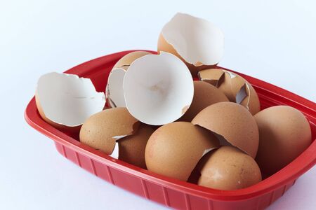 Broken eegshells in red container on white background